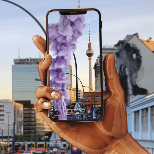 Straße in der Nähe des Alexanderplatzes in Berlin. Eine Hand mit Smartphone. Auf dem Handyscreen zu sehen: Eine digitale Rauchskulptur von Judy Chicago, im Hintergrund der Alexanderplatz mit dem Berliner Fernsehturm.